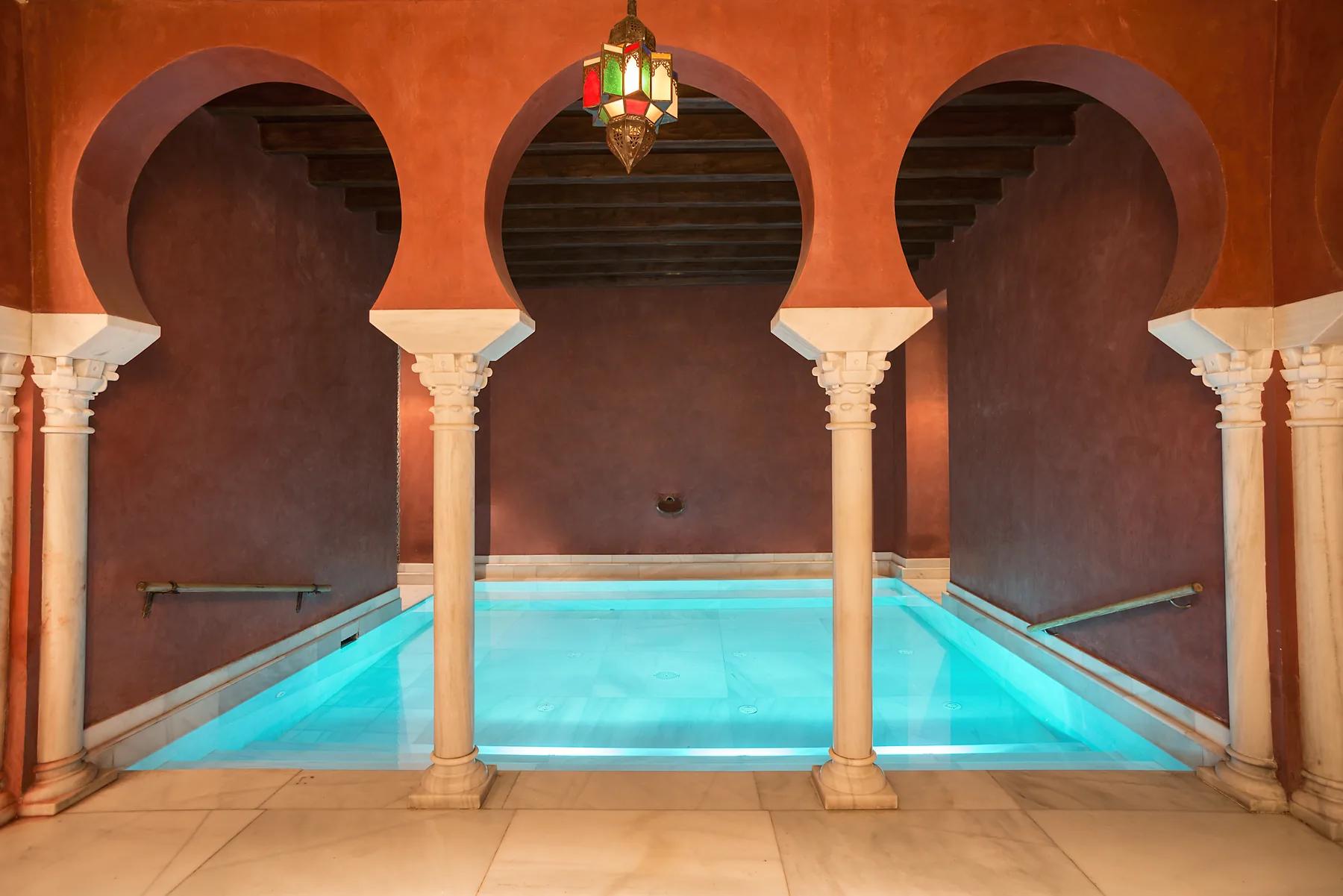 Triple arco califal sobre piscina templada con lámpara colorida