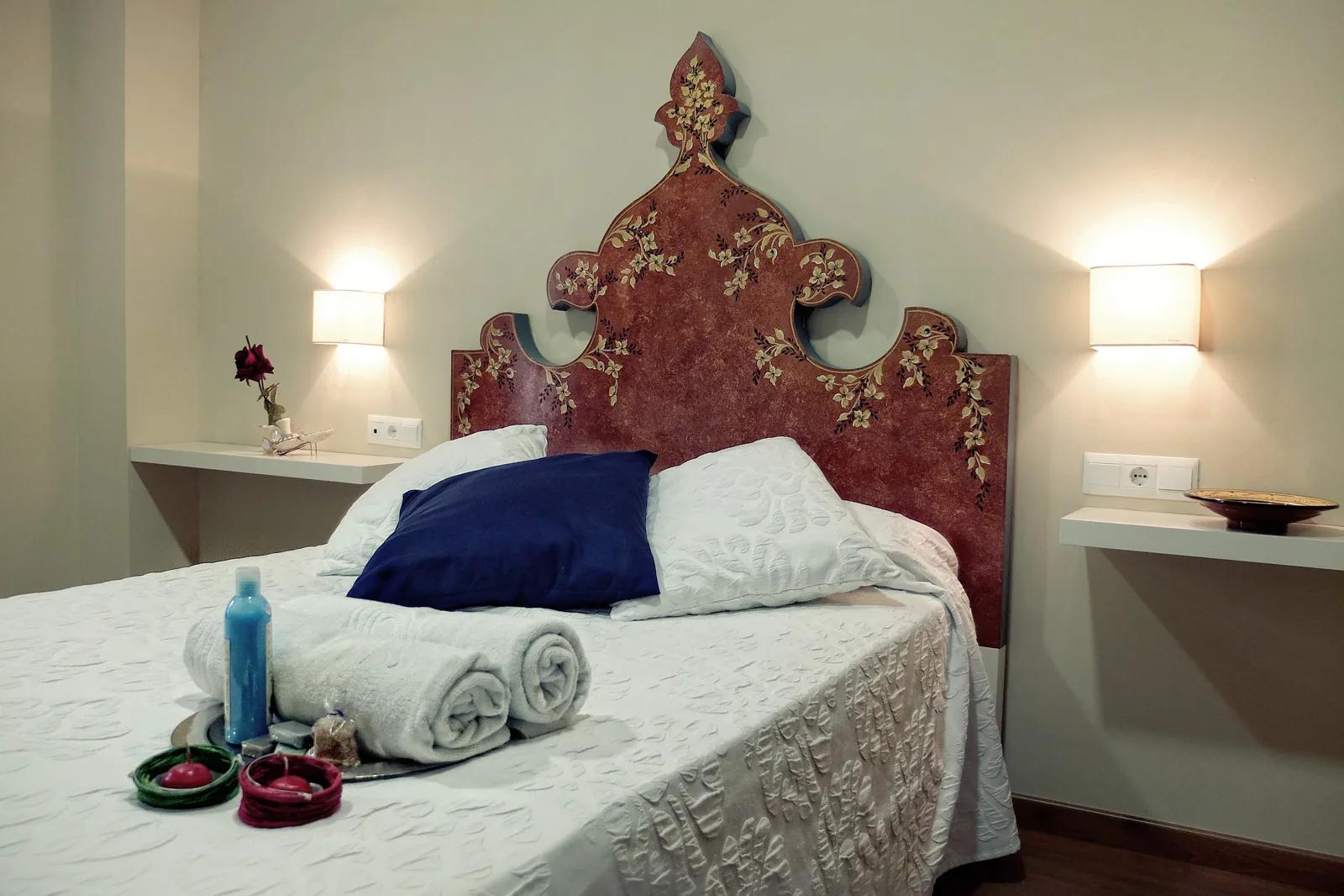 Habitación con cabecero floral, toallas y velas