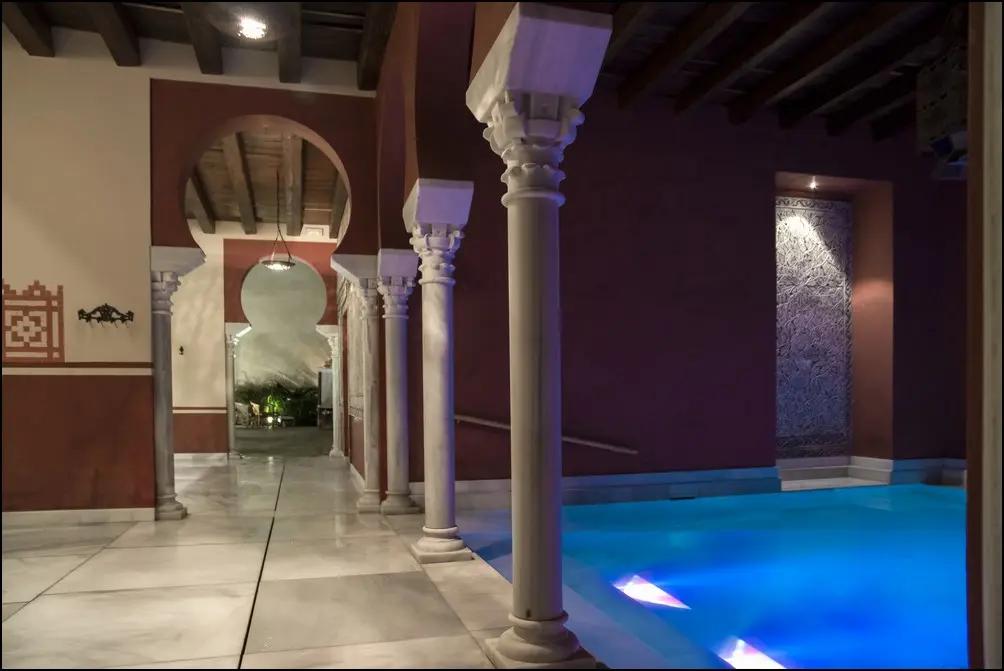 Piscina caliente iluminada bajo arcos de piedra